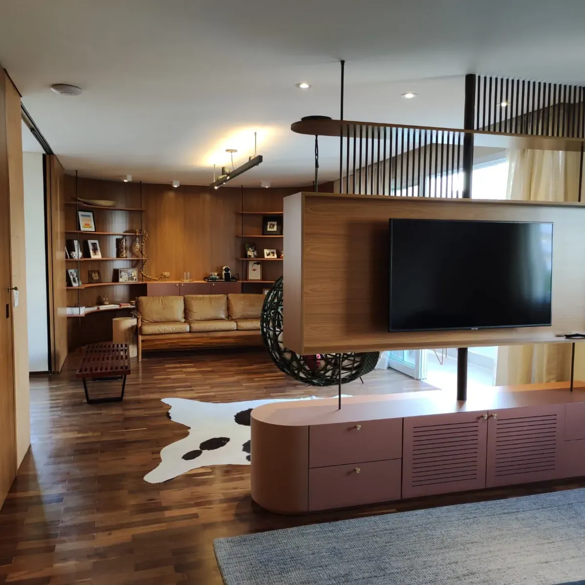 Sala com painel de TV suspenso e estante em madeira